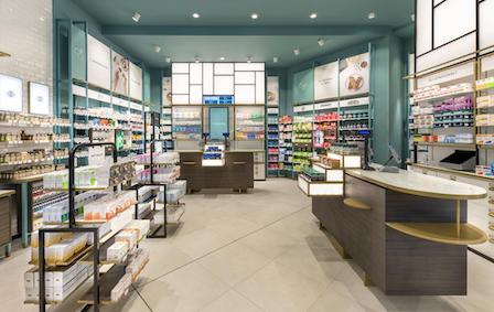 An empty, brightly lit pharmacy with products neatly organised on shelves.