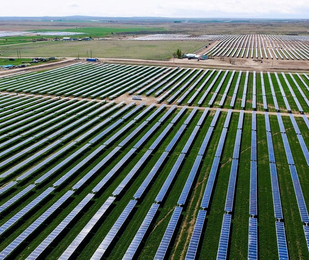 An expansive solar farm with rows upon rows of solar panels arranged in neat, parallel lines, stretching out towards the horizon.