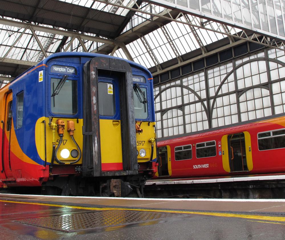 Two red, blue, yellow and orange-striped trains stationing in a tall glass structure.
