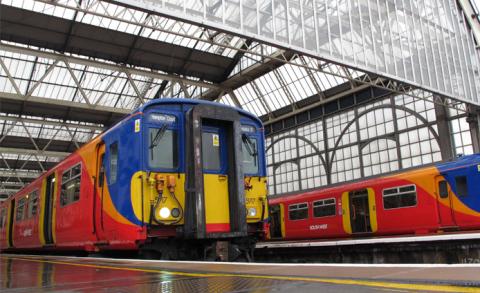 Two red, blue, yellow and orange-striped trains stationing in a tall glass structure.