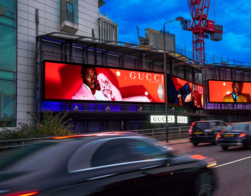 A billboard showing ads for Gucci, displayed on a busy road on Cromwell Road