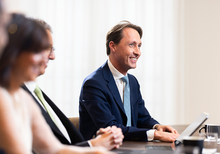 Man in suit smiling at meeting table in a professional table.